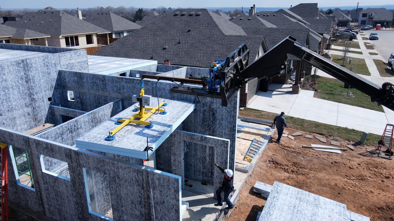 Crane lifting a composite wall panel into place on a modular home shell