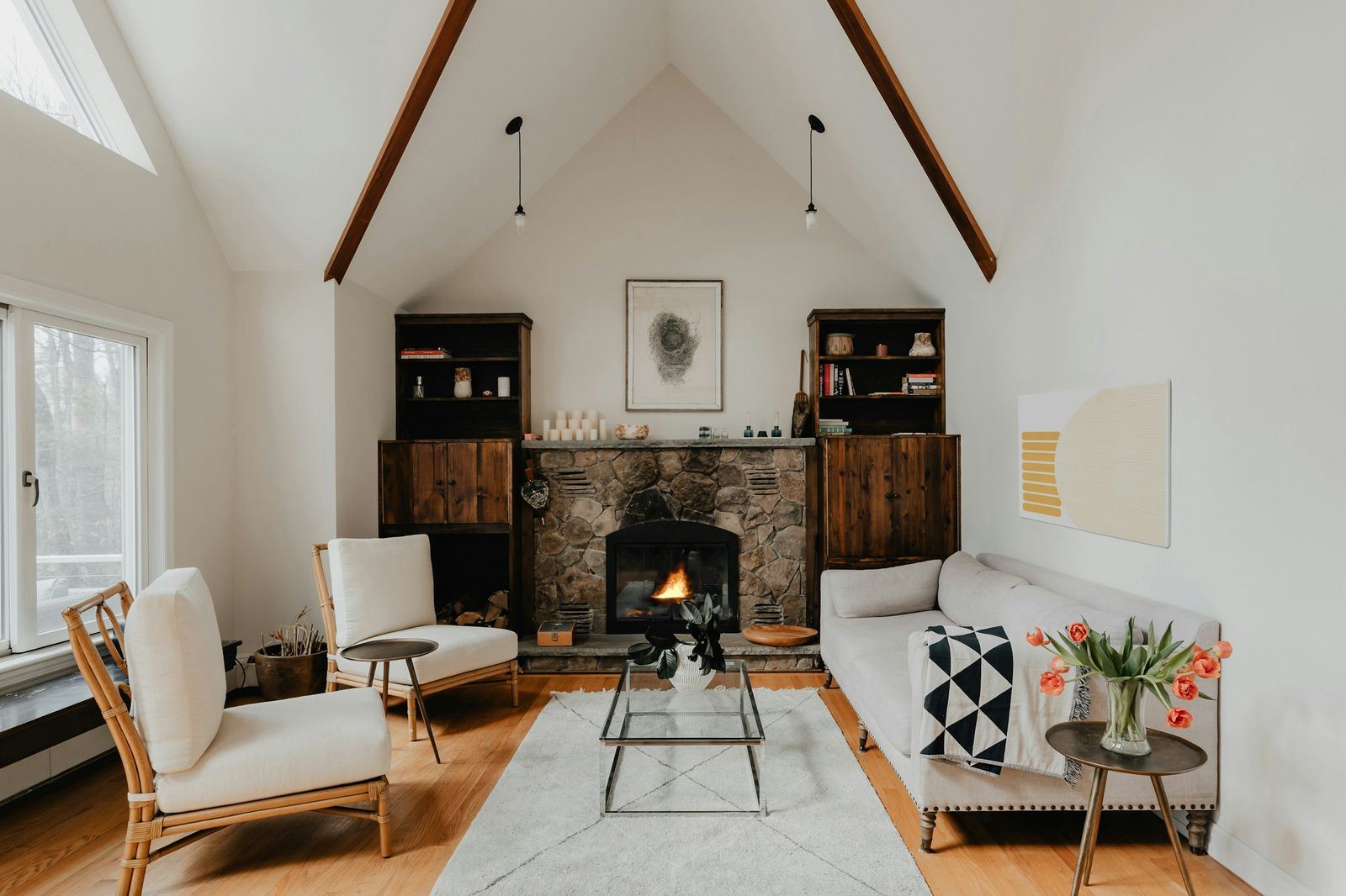 Bright vaulted living room with a stone fireplace and lounge chairs