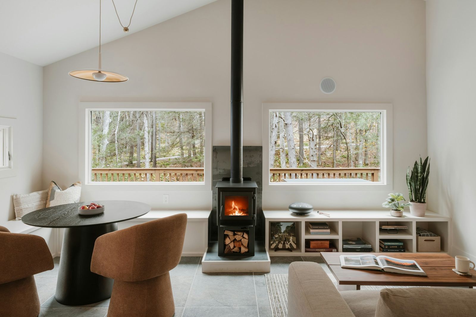 Modern wood stove beside large windows in a minimalist living space